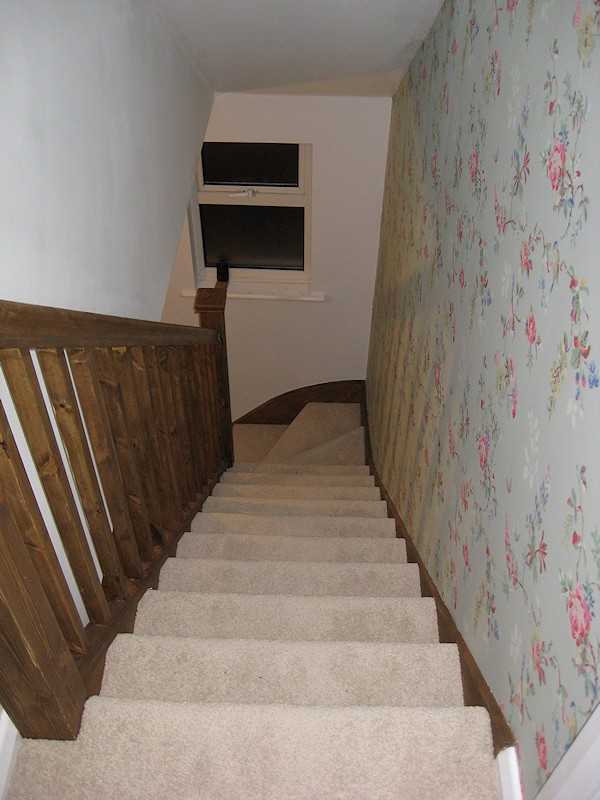 A single turn winder staircase constructed in softwood and finished in dark wood stain.