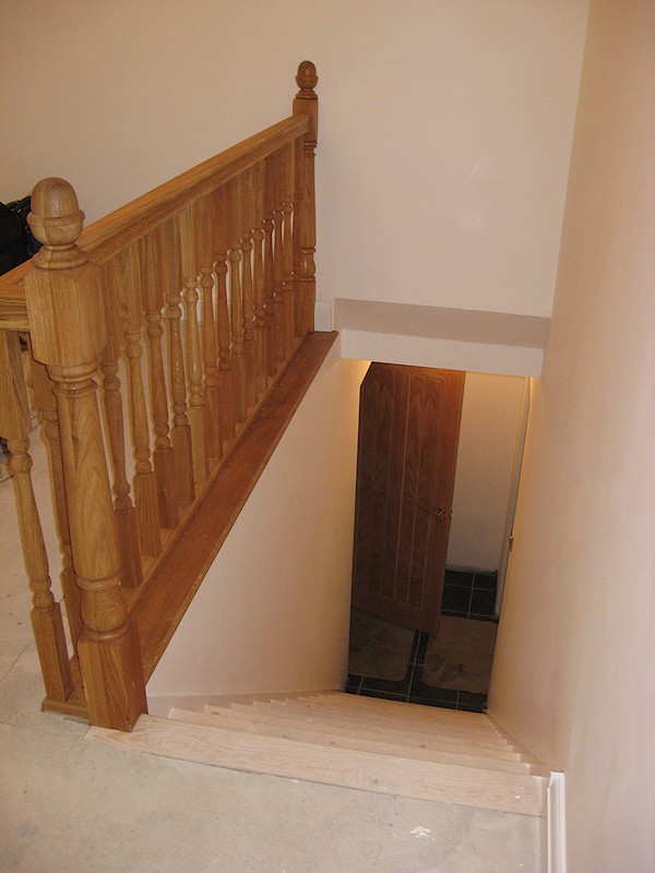 A simple straight flight staircase between enclosed walls, brought to life with oak balustrade on landing.