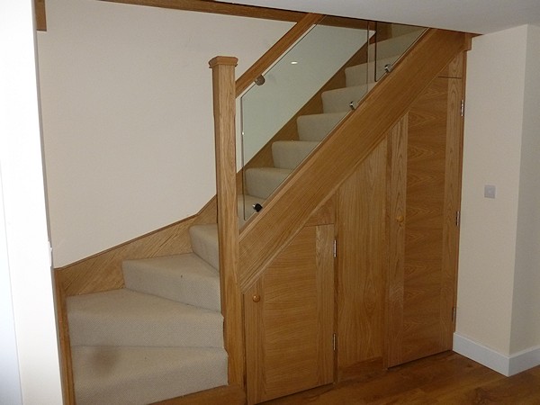 An oak single turn, winder staircase with glass balustrade.