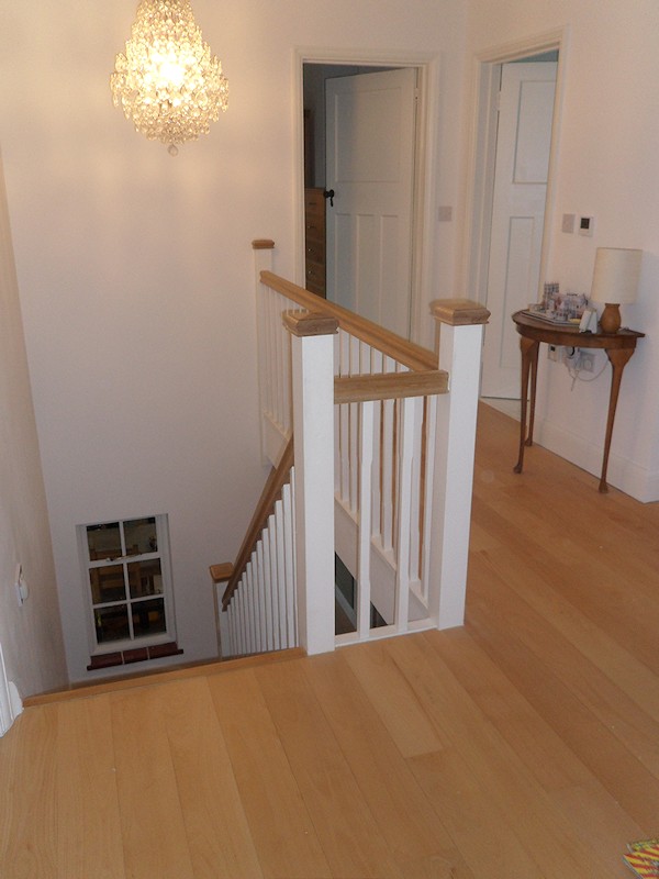 A softwood winder staircase for a loft conversion, painted white with feature oak handrail and newel caps.