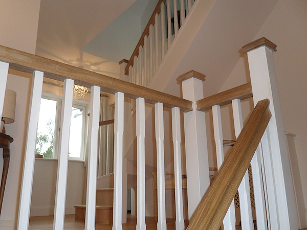 A softwood winder staircase for a loft conversion, painted white with feature oak handrail and newel caps.