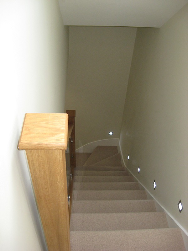 This staircase has an ultra modern feel with glass balustrade and lighting mounted above the wall string.